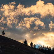 Photo of clouds and sunlight over a hill 