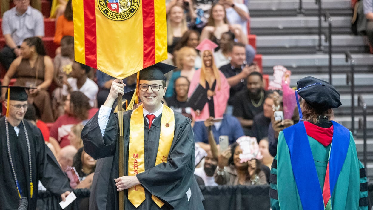 Joseph Govreau, student marshal and outstanding student in social work, carries the banner for the School of Social Work during commencement ceremonies last May